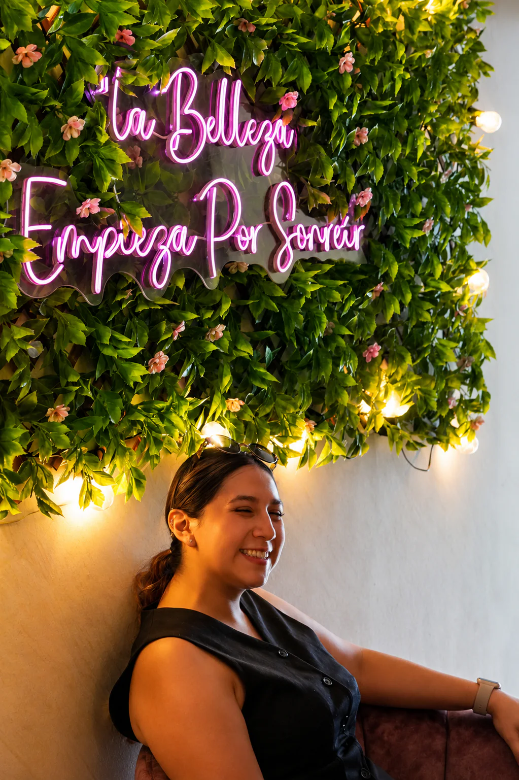 Clienta sonriendo bajo el letrero La Belleza Empieza Por Sonreír en Esbell Spa